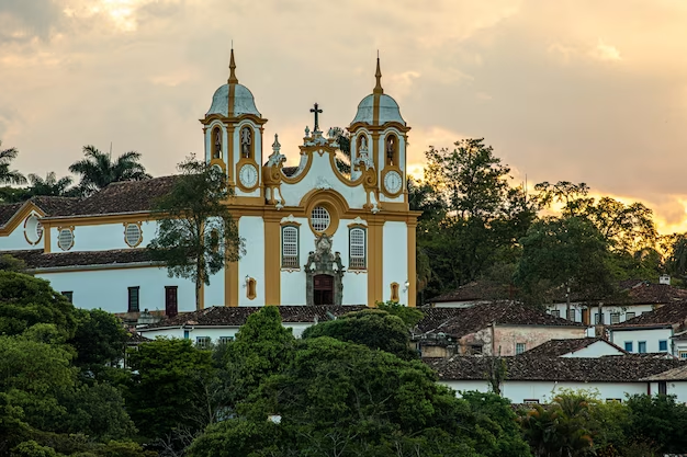 Ah, Tiradentes, uma bela cidade histórica no coração de Minas Gerais! Aqui estão algumas informações úteis para a sua viagem turística a Tiradentes: Clima: Tiradentes possui um clima tropical de altitude, o que significa que as temperaturas são amenas durante todo o ano. No entanto, é bom estar preparado para mudanças de temperatura, especialmente durante as noites, quando pode esfriar um pouco mais. Melhor época para visitar: A melhor época para visitar Tiradentes é durante a temporada seca, que vai de abril a setembro. Nesse período, as chuvas são menos frequentes e as temperaturas são mais amenas, tornando a experiência mais agradável. Atrações turísticas: Tiradentes é rica em história e cultura. Não deixe de visitar o Museu da Liturgia, a Igreja Matriz de Santo Antônio, a Rua Direita com suas lojas e restaurantes charmosos, e o Largo das Forras, onde ocorre a famosa Feira de Artesanato aos finais de semana. Gastronomia: A cidade é conhecida por sua culinária mineira tradicional. Experimente pratos típicos como o feijão tropeiro, o frango com quiabo e a famosa canjiquinha com costelinha. Passeios ao redor: Além de Tiradentes, você também pode aproveitar para visitar a cidade vizinha de São João del Rei, que também possui um centro histórico encantador. Não deixe de fazer um passeio de Maria Fumaça, uma locomotiva a vapor que percorre a estrada de ferro entre as duas cidades. Hospedagem: Tiradentes oferece uma variedade de opções de hospedagem, desde pousadas charmosas até hotéis boutique. Recomendo reservar com antecedência, especialmente durante feriados e festivais, para garantir o melhor lugar para se hospedar. Lembre-se de sempre respeitar a cultura local, seguir as orientações dos moradores e desfrutar da beleza e tranquilidade desta encantadora cidade histórica. Aproveite a sua viagem a Tiradentes!